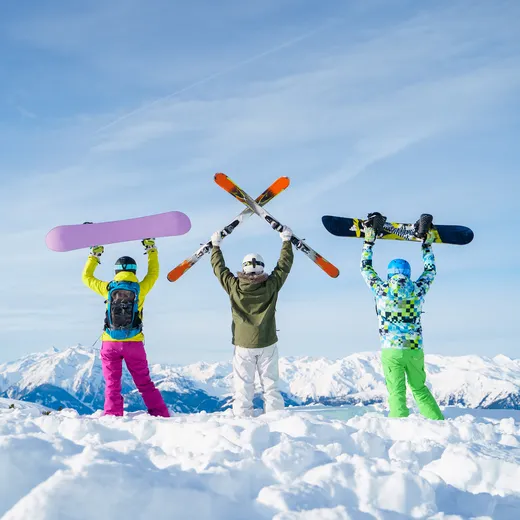 Friends holding skis and boards on a summit